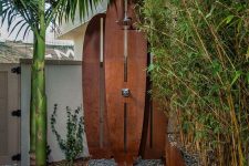 a tropical shower with a wall formed of wooden surf boards, a wooden deck and lots of plants growing around