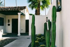 a very chic modern desert-styled front yard with rocks and cacti that line up the stone path to the entrance of the house