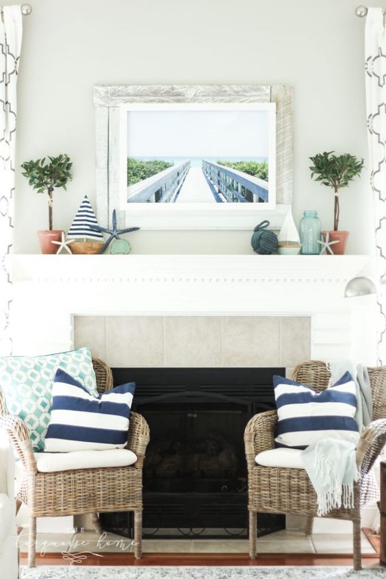 a vintage coastal mantel with potted greenery, mini boats, starfish, a photo in a whitewashed wooden frame and a rope ball