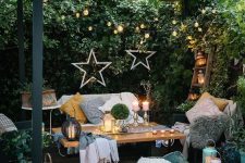 a welcoming summer terrace with a sofa, some chairs, a coffee table, printed rugs, pillows, candles, candle lanterns and star decor