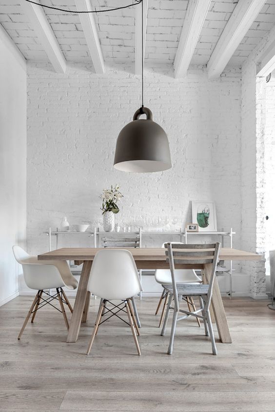 a white Scandinavian dining space with white brick walls and white beams on the ceiling, a lovely dining set and neutral hardwood floors