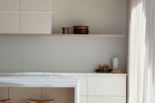 an airy minimalist kitchen in white, with planked cabinetry, an open shelf, neutral curtains and a lovely dining set
