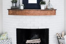 an easy farmhouse summer mantel with greenery arrangements, potted plants, a mirror in a wide frame and some books
