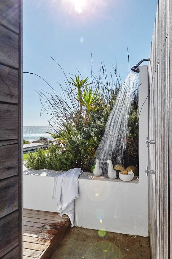 an outdoor shower with a sea view, a wooden deck and a bamboo floor, some shower stuff and towels