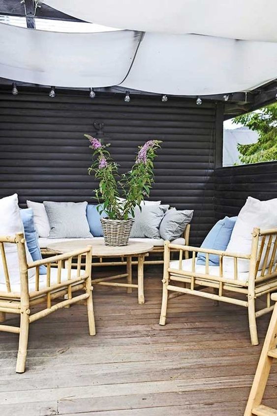 a Scandinavian terrace with a wooden deck, bamboo furniture, muted and neutral textiles and string lights