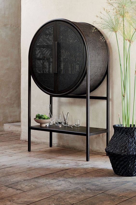 a beautiful black cane home bar of a round shape and with an open shelf is a lovely idea for a modern and refined space