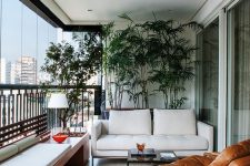 a chic and bold modern balcony as an outdoor living room, with potted plants, a white sofa and an upholstered bench, a wood and leather chair and bright accents