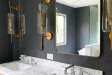 a chic bathroom with a black wallpaper wlal, brass, silver and black metals that look elegant and cohesive in the space