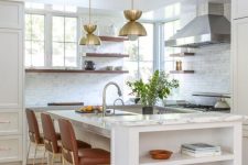 a chic farmhouse kitchen in white, with shaker cabinets, open shelves, brown stools with gold legs, gold pendant lamps and chromatic appliances