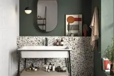 a chic mid-century modern bathroom with green walls, colorful terrazzo tiles on the wall and floor, a cool modern vanity with a metal sink
