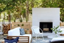 a chic modern terrace with a white fireplace, rattan and wood furniture, neutral upholstery and printed textiles is amazing