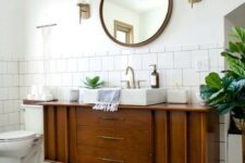 a classic mid-century modern bathroom with white square and penny tiles, a boho rug, a wooden vanity and touches of brass