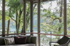 a clean and lovely contemporary screened porch with laconic grey furniture, a wicker chair and lovely views of the lake