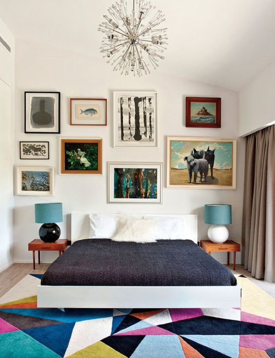 a colorful mid-century modern bedroom with a white bed, stained nightstands, a colorful geo rug, a colorful gallery wall