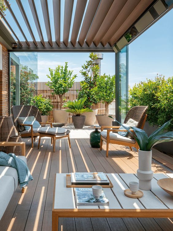 a contemporary and very welcoming terrace with a wodoen deck, wooden furniture, lots of potted plants here and there is amazing