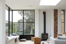 a contemporary living room with a skylight, a large corner window, a daybed, printed pillows and bedding and a black hearth
