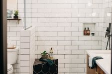 a contrasting black and white bathroom with white subway tiles and black hexagon ones, a stained vanity, black touches