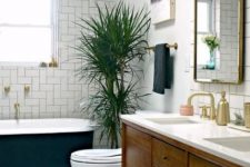 a cool mid-century modern bathroom with a black clawfoot tub, white tiles of various kinds, a stained vanity, a mirror and a potted plant