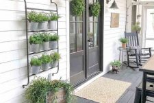 a cool rustic porch with a black deck, doors and furniture, potted greenery, sconces and crates plus a printed rug is lovely