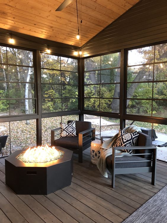 a cozy black screened porch with a fire pit, black chairs and printed pillows plus a cool view of the garden is cool