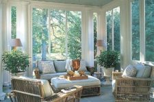 a cozy modern rustic screened porch with rattan furniture, potted plants, lamps and printed pillows is a lovely space
