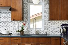 a cozy rich-stained kitchen with graphite grey stone countertops and white geometric tiles on the backsplash