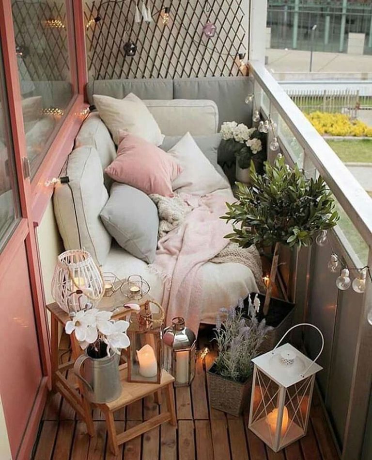 a cute balcony with a sofa with lots of pillows, potted plants and blooms, candle lanterns and string lights is a cool space