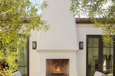 a fab modern outdoor space with a large white stucco fireplace, stained and white chairs and ottomans is a very chic and elegant terrace