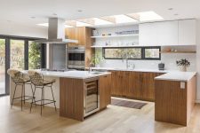 a fantastic mid-century modern stained kitchen with white countertops, a geo tile backsplash, a window and skylights