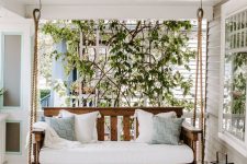 a farmhouse porch with a stained daybed, white and blue pillows, candle lanterns and a blue striped rug is a chic space
