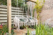 a fresh and welcoming outdoor space with growing greenery and flowers and with macrame hanging chairs that act as swings