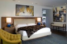 a glam mid-century modern bedroom with a floating bed, matching nightstands, a mustard chair and a bold artwork