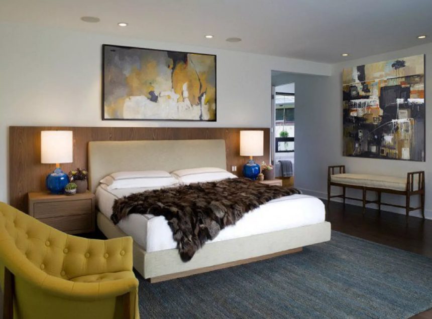 a glam mid century modern bedroom with a floating bed, matching nightstands, a mustard chair and a bold artwork