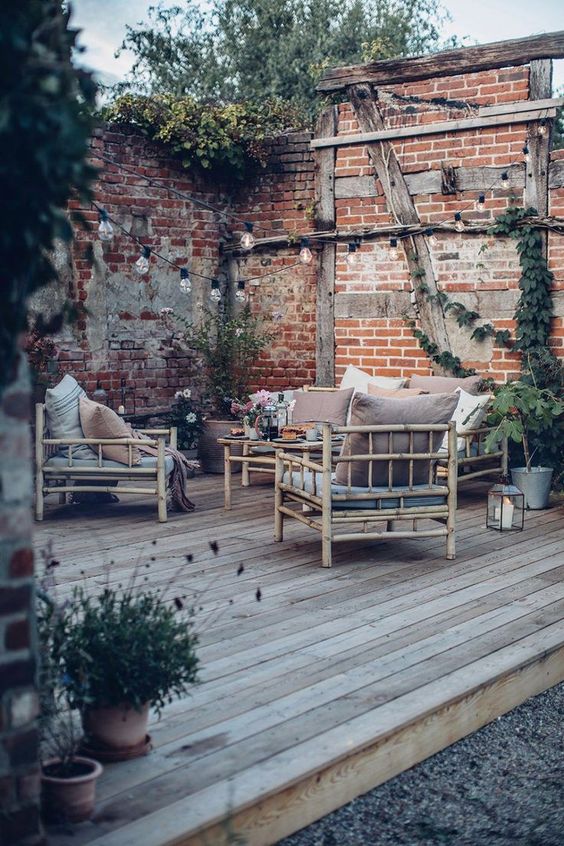 a laid-back deck with simple bamboo furniture, muted color pillows, potted greenery, string lights and candle lanterns