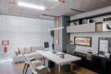a large modern industrial home office that features exposed copper pipes, a large desk with chrome legs and a copper table lamp and they all look nice together