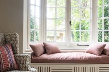 a lovely and cozy space with a bow window finished wiht a built-in daybed, with dusty pink bedding and some shades