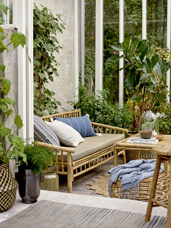 a lovely boho space with a tiled floor, bamboo furniture, printed textiles, potted plants and trees is a very welcoming one