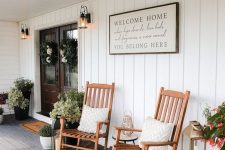 a lovely farmhouse porch styled for summer, with potted greenery, blooms, stained rockers, a candle lantern and a striped rug