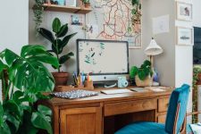 a lovely mid-century modern home office nook with a stained desk, a navy chair, potted plants, a map artwork and a mini gallery wall