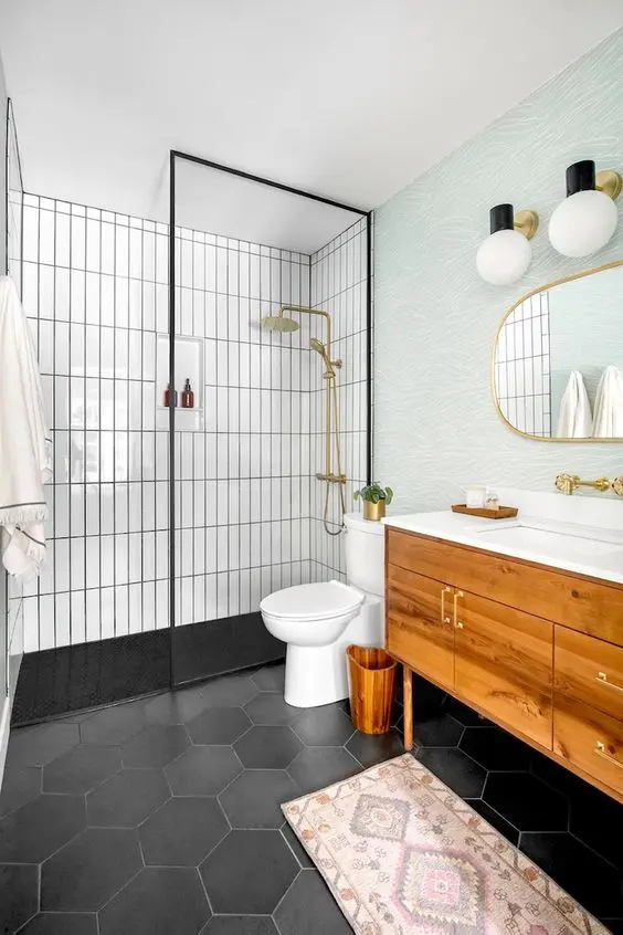 A mid century modern bathroom with white skinny and black hex tiles, a stained vanity, a blue accent wall, gold fixtures