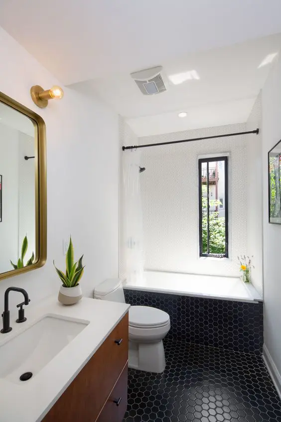 a mid-century modern bathroom with white walls and black hex tiles, a stained vanity, gold touches and black fixtures
