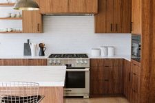 a mid-century modern kitchen with dark stained cabinets, a rich stained kitchen island, white stone countertops and a white skinny tile backsplash