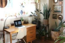 a mid-century modern working space with a small stained desk, a white chair, a printed rug, potted plants, a gallery wall and a table lamp