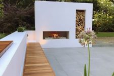 a minimalist terrace with a white fireplace with fireood storage, a cool bench of sutcco and wood is amazing to relax here