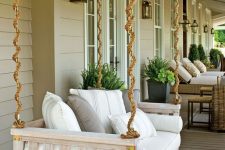 a neutral hanging daybed with printed pillows and bedding is a perfect idea for a farmhouse porch and looks cool
