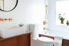 a neutral mid-century modern bathroom with geometric and penny tiles, a tub clad with wood and a stained vanity, gold fixtures