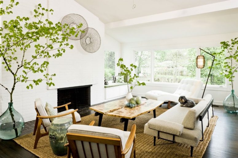 a neutral mid-century modern living room with a brick fireplace, a white lounger and neutral seating furniture, a living edge table and some greenery
