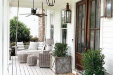 a neutral rustic porch with grey wicker furniture, potted greenery, candle lanterns and printed textiles is a cool space