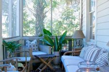 a pretty tropical screened porch with wicker furniture, printed pillows, potted plants, candle lanterns and lamps is cool