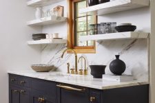 a refined mid-century modern kitchen with dark grey cabinets, open shelves of white stone, a backsplash and countertops